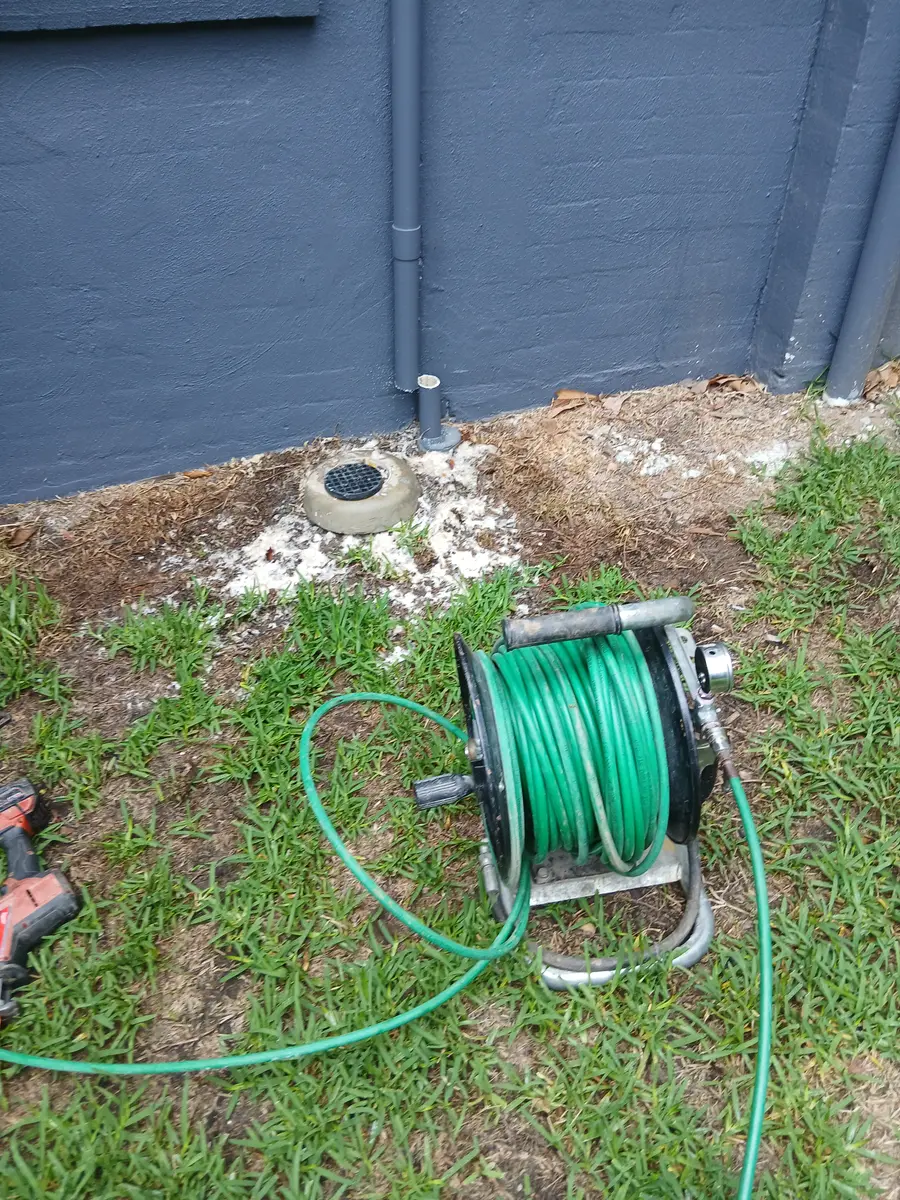 Garden hose reel beside a newly capped outdoor drainage point