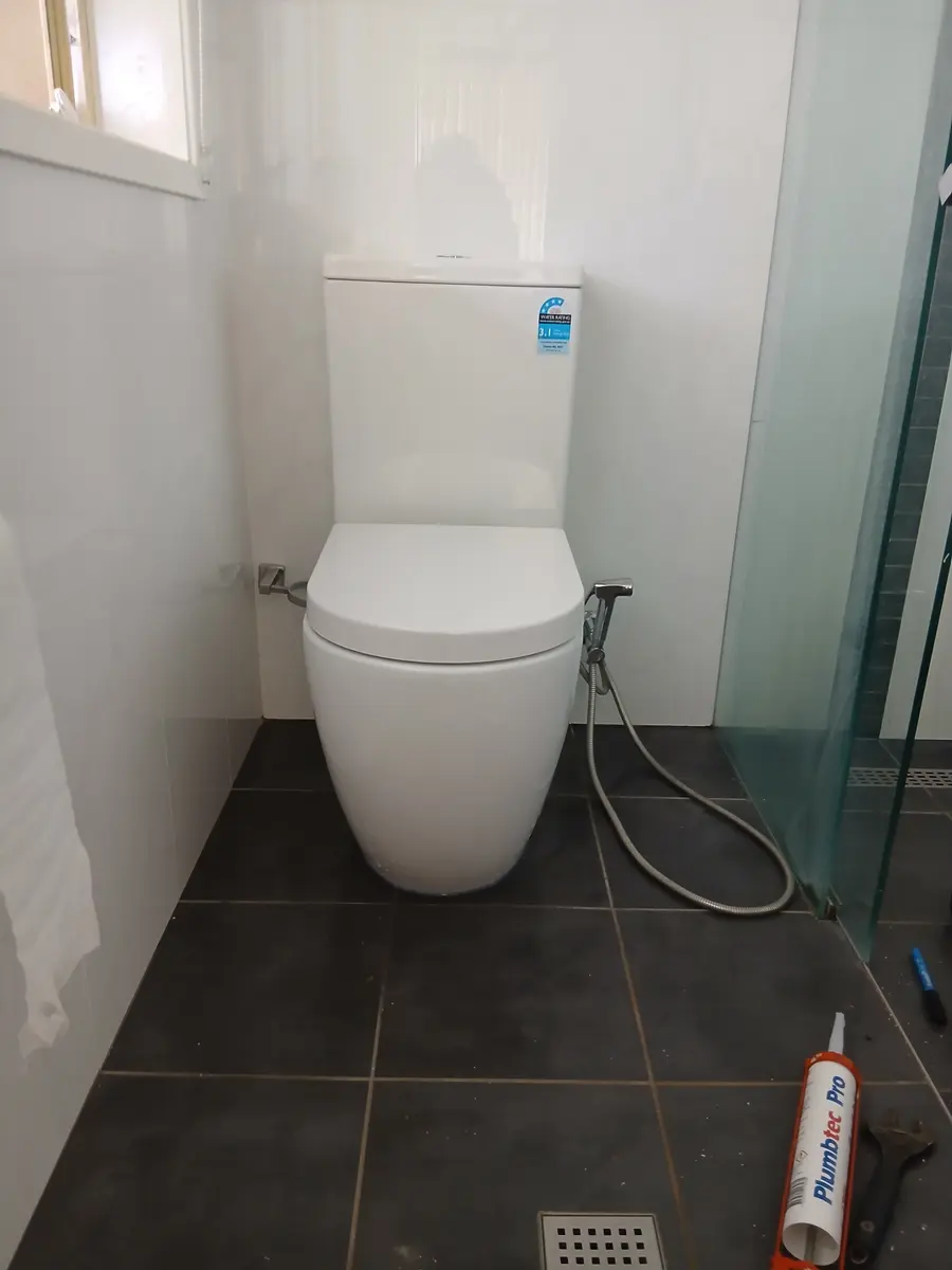 New back-to-wall toilet suite installed on a charcoal-tiled bathroom floor