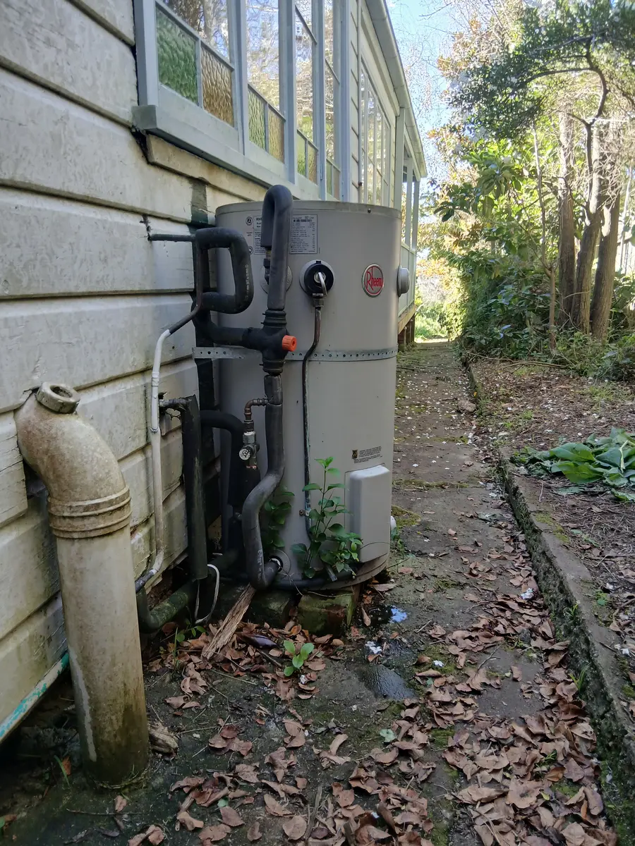 Heat-pump hot water system installed beside a weatherboard home